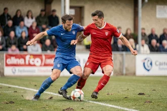 Match de football amateur à Bergerac avec deux joueurs en duel sur la pelouse lors d'une rencontre de championnat régional